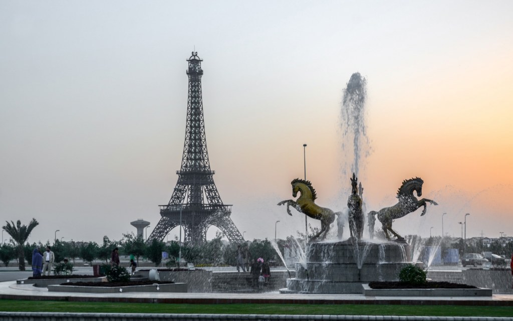 A replica of Paris' Eiffel Tower in Bahria Town Lahore in front of a fountain and a monument