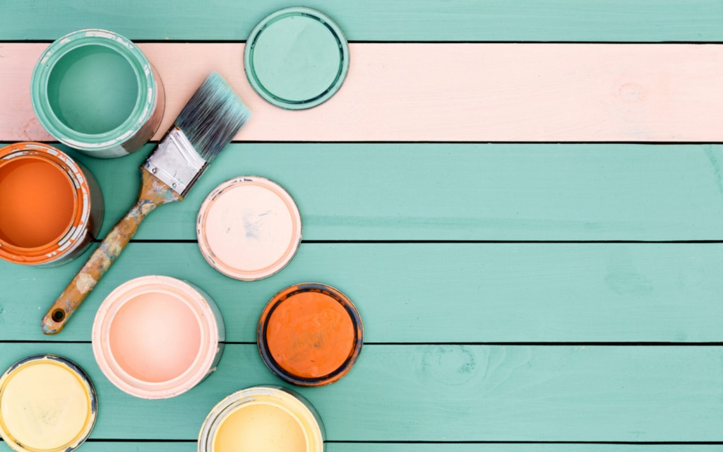 wooden floor boards under yellow, pink, orange and green paint cans