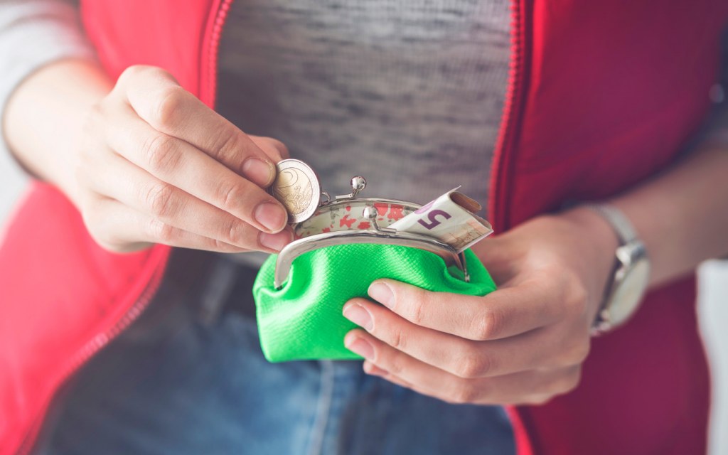 A woman taking out some cash and coins from her clutch