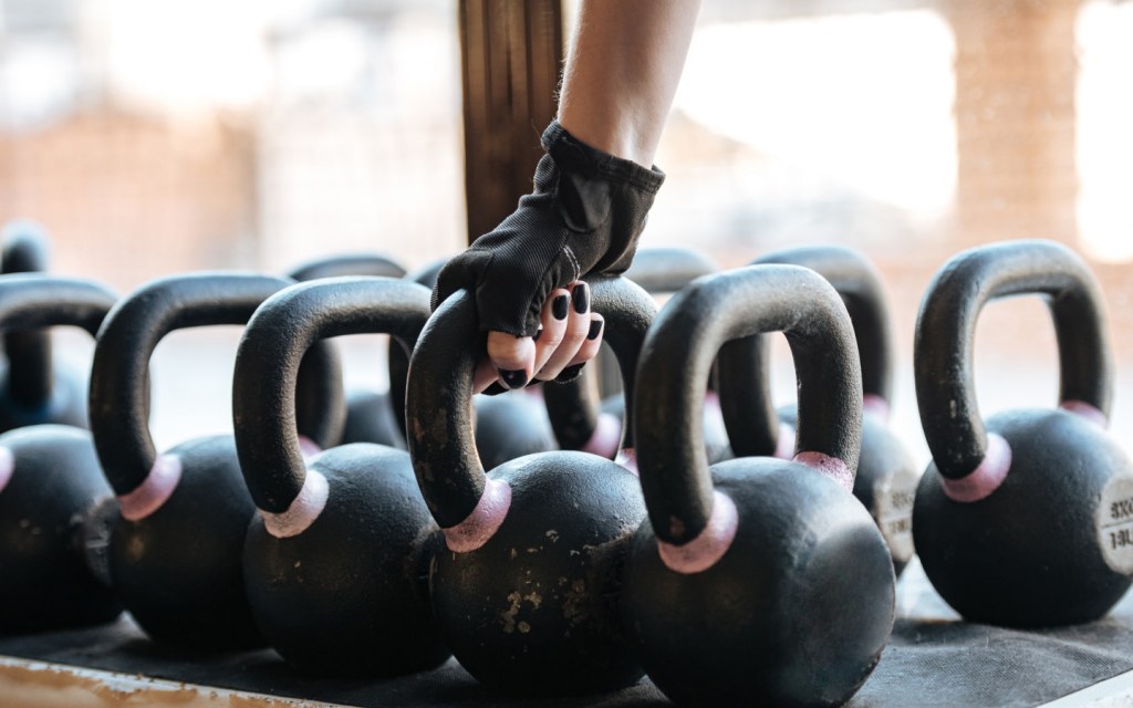 A woman taking kettlebell during fitness course in gym