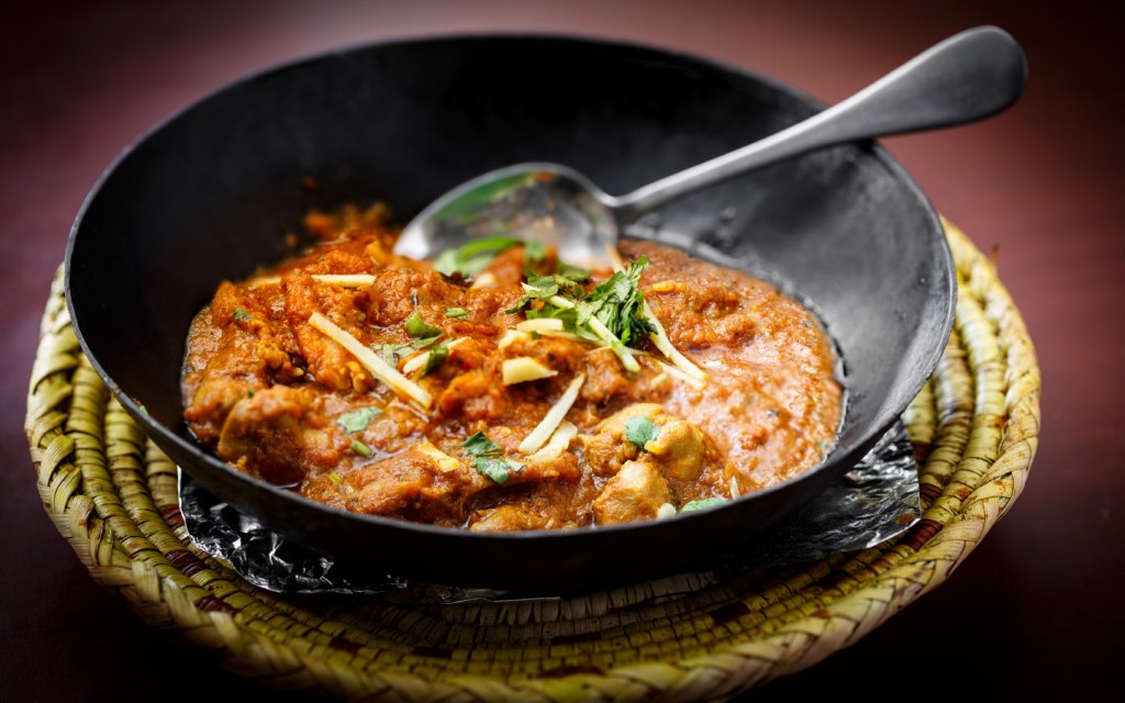 Traditional Karahi in wrought iron pot with ginger on top