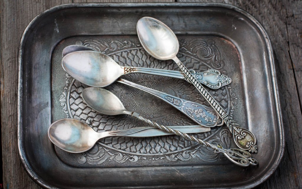 Vintage silver spoons placed in an old plate
